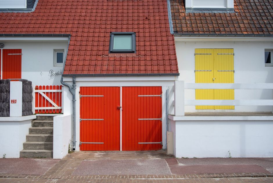 Painted house facade with coloured doors and a tile roof