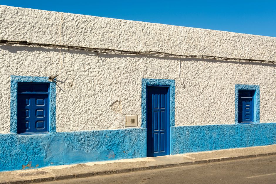 Painted house facade in blue and white under a clear sky