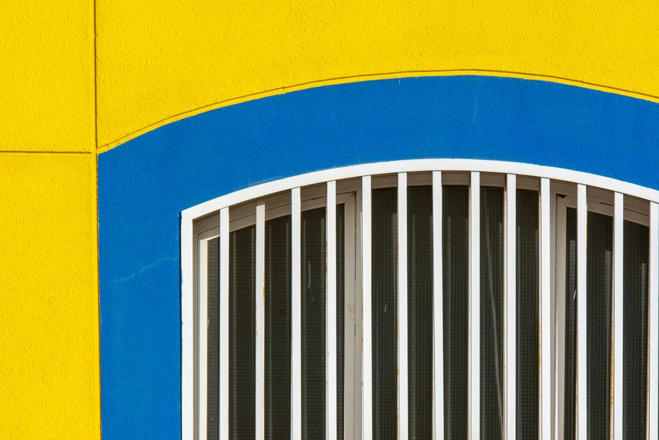 Painted house front in yellow and blue around an arched window